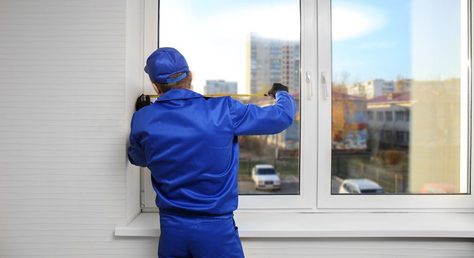 Sharp Glass contractor fixing and measuring up a glass window